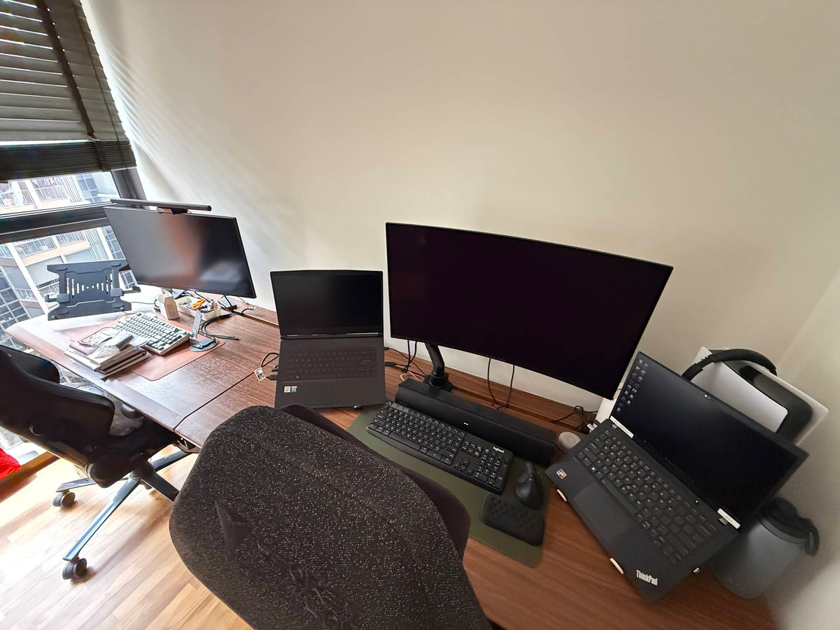 ULTI Arc Pro walnut standing desk in a blue-lit gaming and work setup