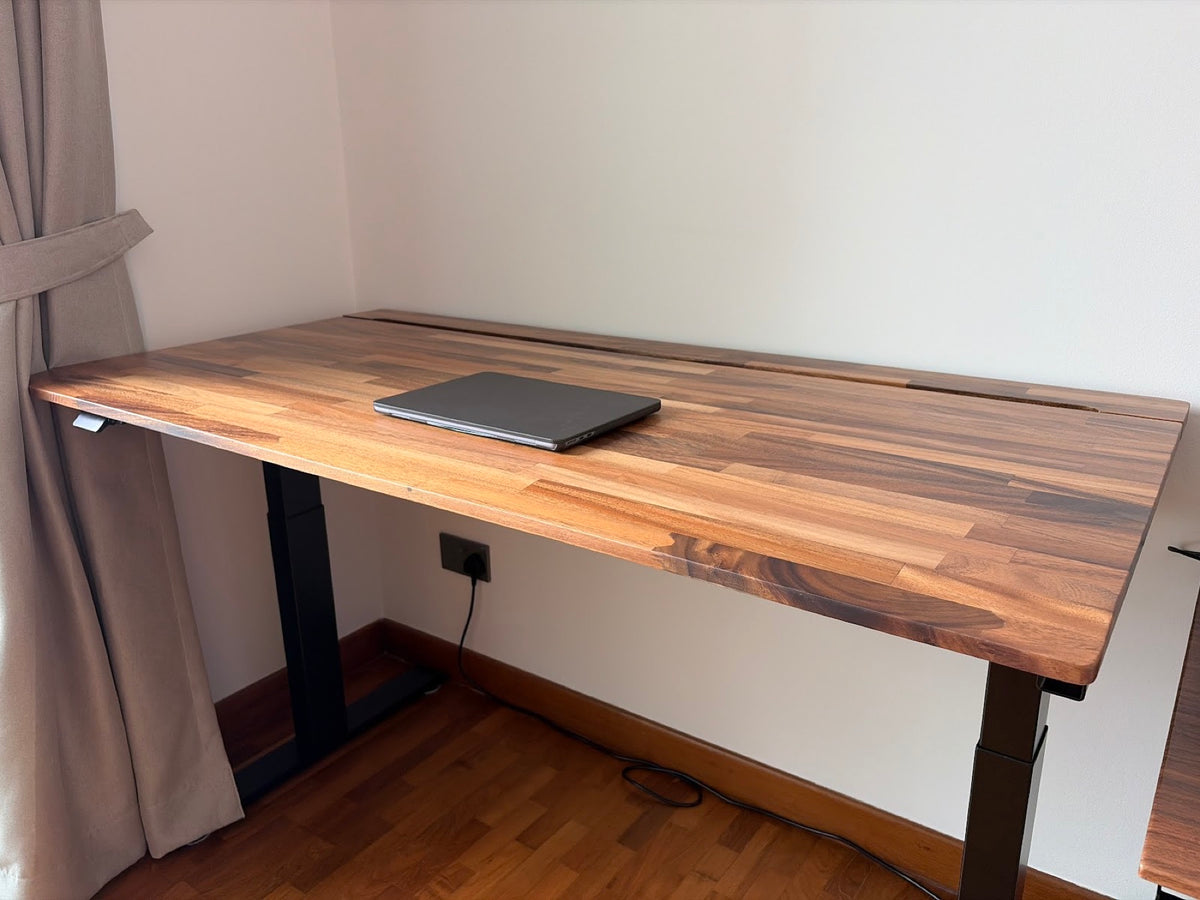 Wide solid-wood ULTI standing desk in a sunlit room